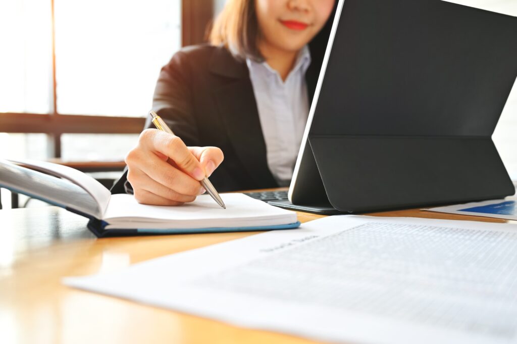 Audit business woman working with notebook and tablet on desk.