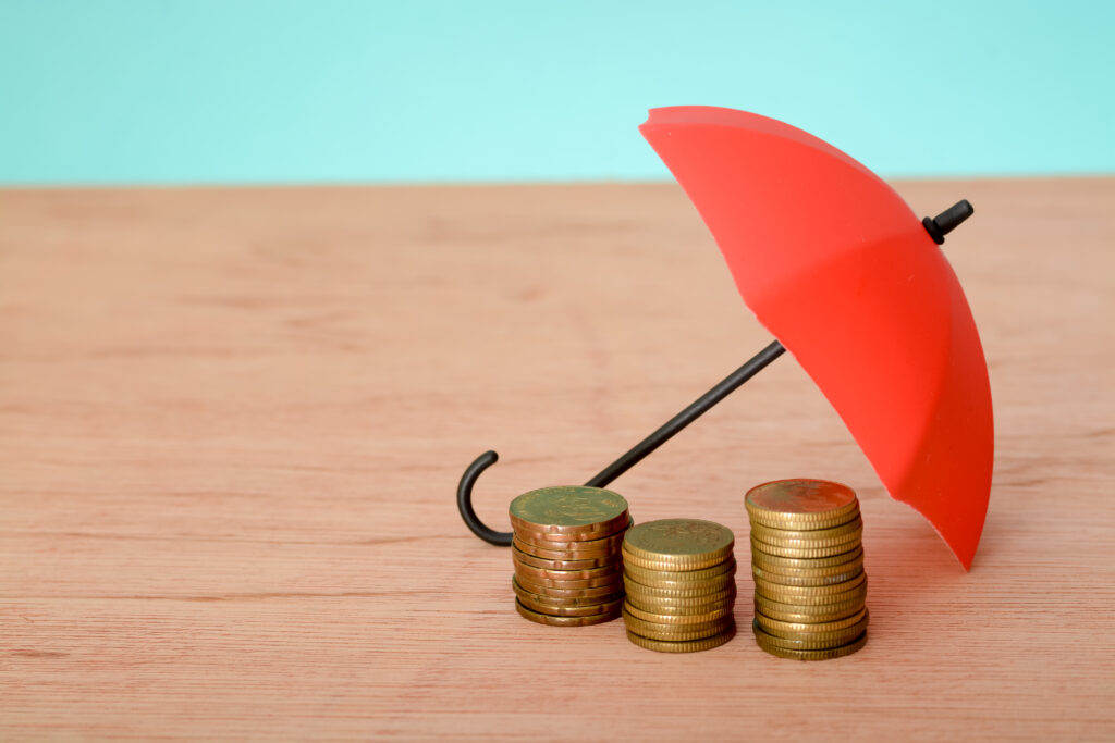 Red umbrella and coins with copy space. Money protection and safety assurance concept
