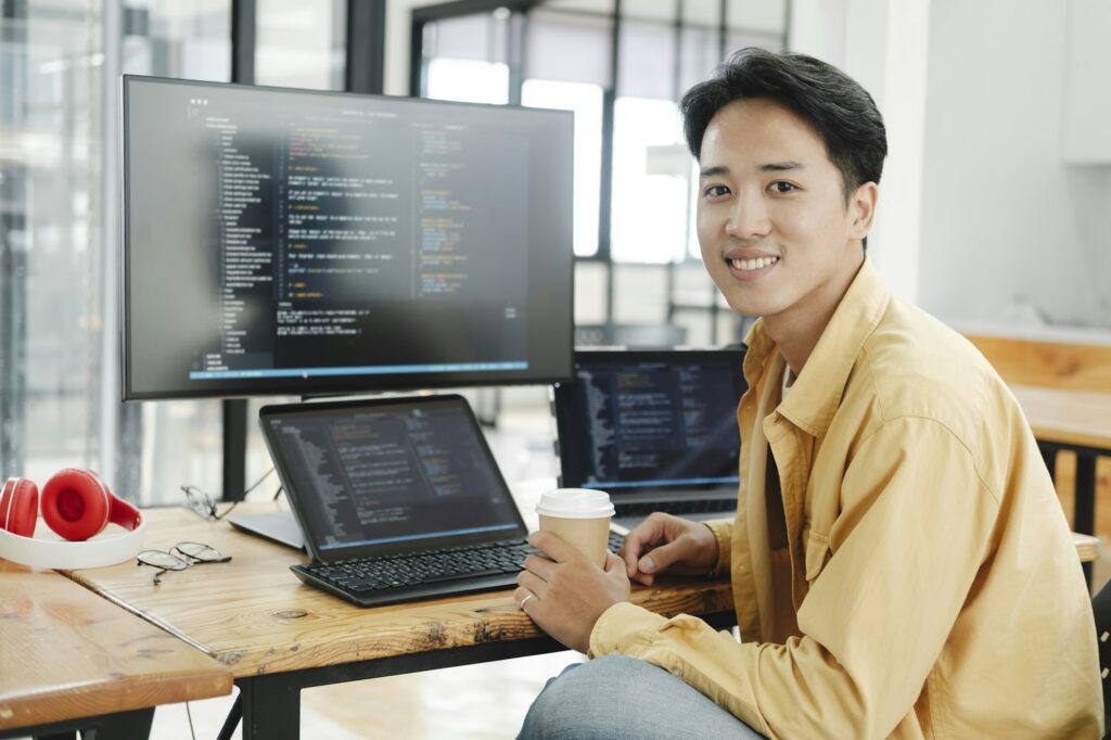 Young programmer working on desktop PC in office of software company.